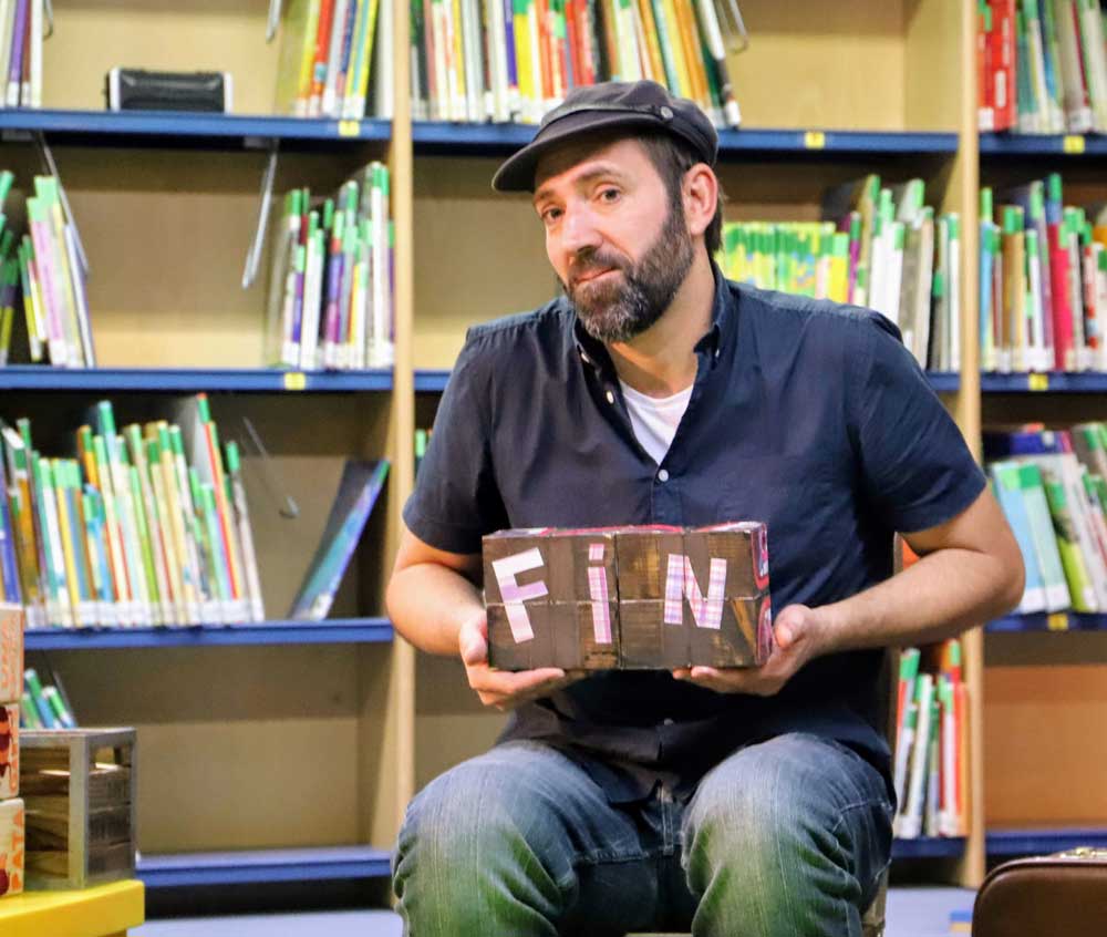 Juan Malabar, cuentacuentos con marionetas, mostrando un cartel con la palabra FIN al terminar su historia.